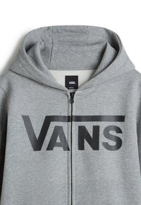 Sudadera con cremallera gris de forro polar con un logo negro de "VANS" en el pecho, que cuenta con una capucha con cordón y una textura suave.