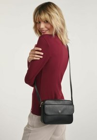 Czarna skórzana torba na ramię o teksturowanym wykończeniu, prostokątnym kształcie, złotych akcentach i jednym regulowanym pasku.