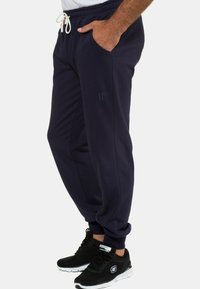 Mjuka navybyxor i bomullsblandning med dragsko i midjan, sidofickor och subtil logotypdetalj på låret. Lämpliga för avslappnad användning.