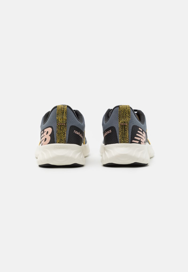 Zapatillas deportivas con una parte superior de malla gris, detalles en negro, una franja dorada y una suela blanca y texturizada. Logo de "New Balance" en rosa.