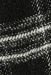 Tela en blanco y negro que presenta un tejido texturizado con un patrón en zigzag. La superficie parece suave, con variaciones en el grosor de los hilos.