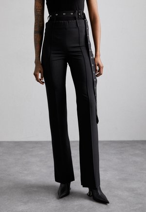 Pantaloni negri cu talie înaltă, cu închidere laterală prin capse, accente metalice și design drept. Materialul pare neted, cu un ușor luciu.