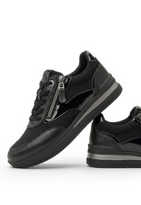 Ζευγάρι μαύρα casual sneakers με κορδόνια, πλαϊνά φερμουάρ και λείες και γυαλιστερές λεπτομέρειες πανέλων σε λευκό φόντο.