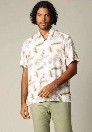 Chemise à manches courtes avec boutons, de couleur blanche, ornée d'un motif de feuilles tropicales et de fleurs en beige et rose. Tissu léger, coupe décontractée.