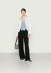 Jaqueta de ganga, blusa azul clara, calças largas pretas e ténis pretos. Mala com riscas brancas e pretas. Design simples com uma estética casual.