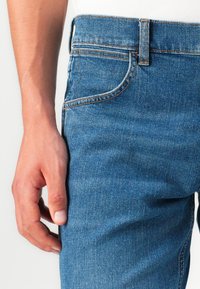 Denim jeans in middelblauw, met een klassieke vijf-pocketontwerp, subtiele stikdetails en een rechte pasvorm, met een gladde textuur.