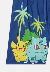 Shorts de bain bleus avec des graphismes de Pikachu et Bulbizarre, ornés de palmiers verts, avec une taille élastique et un cordon de serrage pour l'ajustement.
