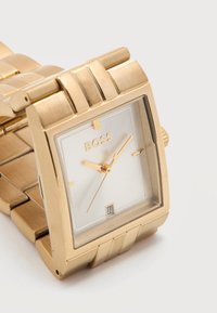 Ορθογώνιο χρυσό ρολόι χειρός με λευκό καντράν, χρυσά δείκτες, ένδειξη ημερομηνίας στη θέση 6, και μεταλλικό μπρασελέ, δείχνει ώρα 10:10:40.