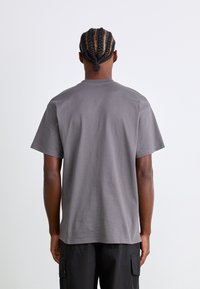 Grijze katoenen t-shirt met korte mouwen, ronde halslijn en een gladde textuur. Zichtbare stiksels langs de zoom en schouders.