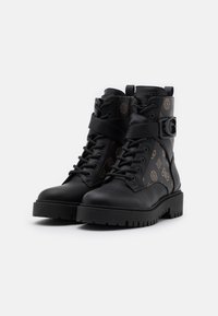 Stivali da combattimento neri in pelle con lacci anteriori, altezza alla caviglia e lato decorato, con un accento a fibbia e suola in gomma spessa.