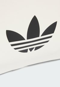 Borsa bianca con una superficie texturizzata che presenta un grande logo trefoil nero di Adidas e tre strisce orizzontali alla base.