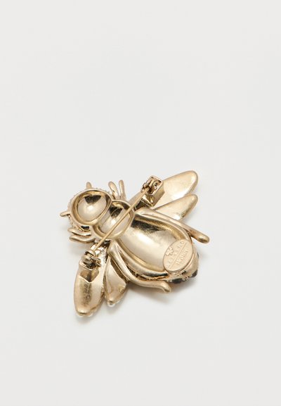 Καρφίτσα σε σχήμα μέλισσας με χρυσό τόνο, με λεπτομερή φτερά και πίσω κούμπωμα, τοποθετημένη σε απλό λευκό φόντο.