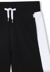 Shorts de jogging noirs avec un panneau latéral blanc, une taille élastique à cordon de serrage et une étiquette BOSS. Fabriqués en tissu doux et texturé.