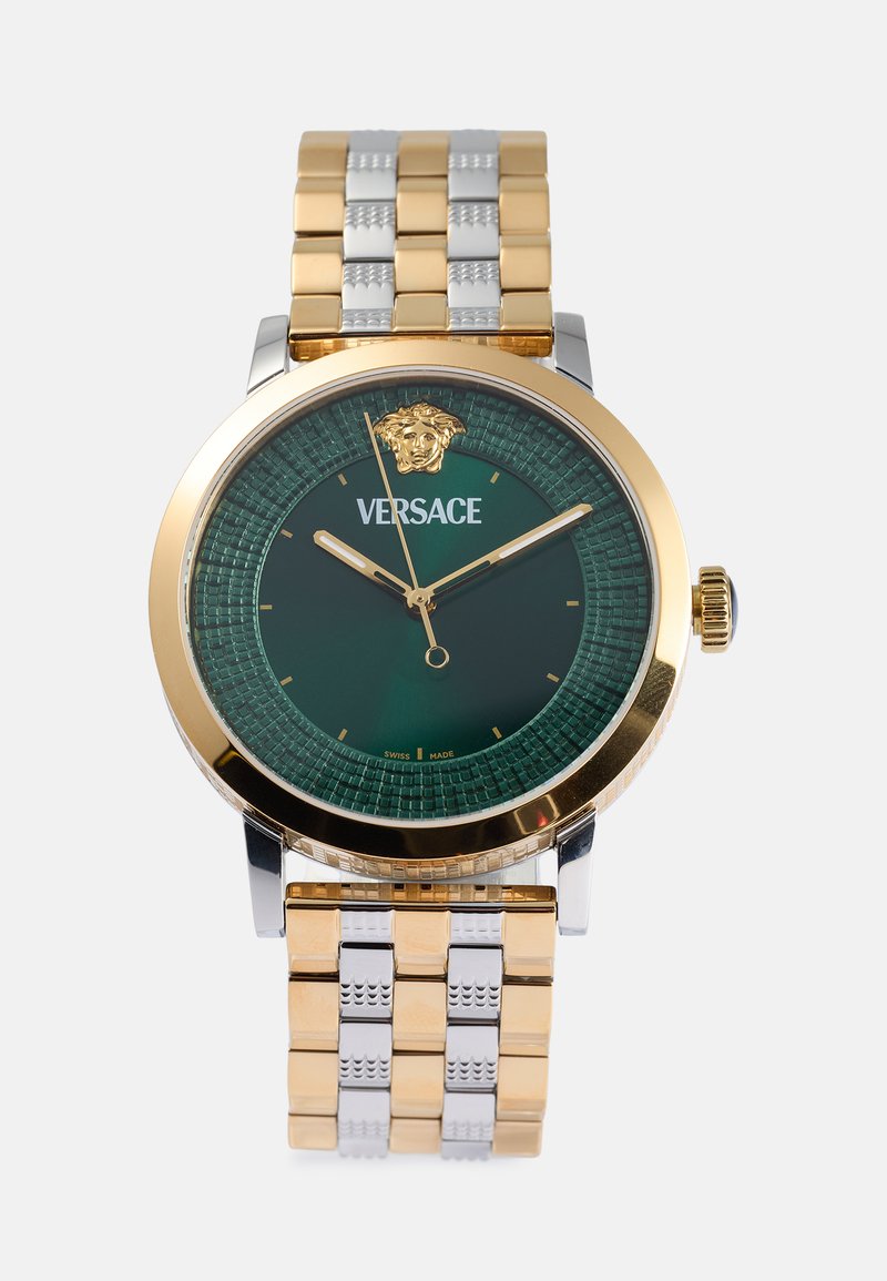 Arany- és ezüstszínű fém óra zöld, textúrázott számlappal, Versace logóval, oroszlánfej díszítéssel és két színű fém karkötővel.