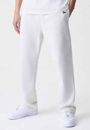 Pantalones de chándal de color gris claro, hechos de una tela suave, con una cintura elástica y bolsillos laterales, combinados con zapatillas blancas.
