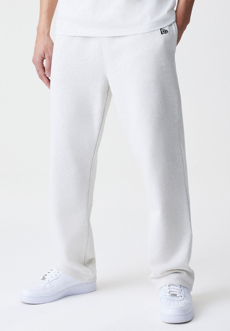 Pantalones de chándal de color gris claro, hechos de una tela suave, con una cintura elástica y bolsillos laterales, combinados con zapatillas blancas.