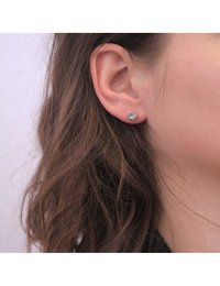 Orecchini a perno rotondi con strass trasparenti montati su una base metallica. Gli orecchini sono piccoli, progettati per orecchie forate e si adattano perfettamente.