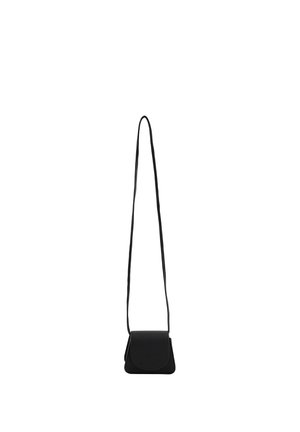 Lille sort læder crossbody taske med lang tynd strop og afrundet flaplukning, vist hængende mod en hvid baggrund.