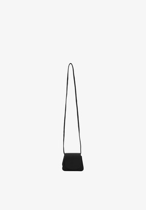 Kleine schwarze Leder-Crossbody-Tasche mit langem dünnem Riemen und abgerundetem Klappenverschluss, an einem weißen Hintergrund hängend gezeigt.