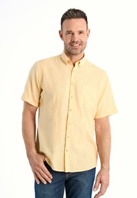 Korte mouwen, overhemd met knopen in een lichtgele stof met een subtiele textuur, voorzien van een borstzak en rozenknopen. Draag het met donkere jeans.