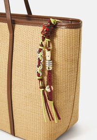 Borsa a spalla in paglia intrecciata con inserti in pelle marrone, caratterizzata da un colorato tassello decorativo realizzato con perline e cordini intrecciati.