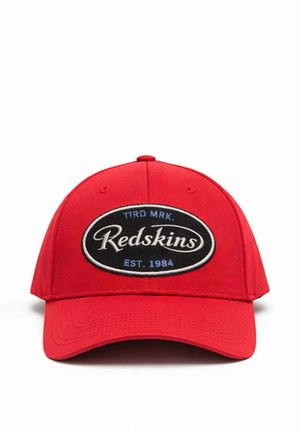 Casquette de baseball rouge avec un patch ovale noir portant l’inscription « TIRD MRK. Redskins EST. 1984 » en texte blanc et bleu sur le devant.