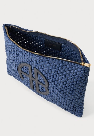 Ναυτικό μπλε υφασμάτινο clutch με χρυστό φερμουάρ και μαύρο λογότυπο "AB" στο μπροστινό μέρος, μερικώς ανοιχτό που δείχνει την εσωτερική υφή.