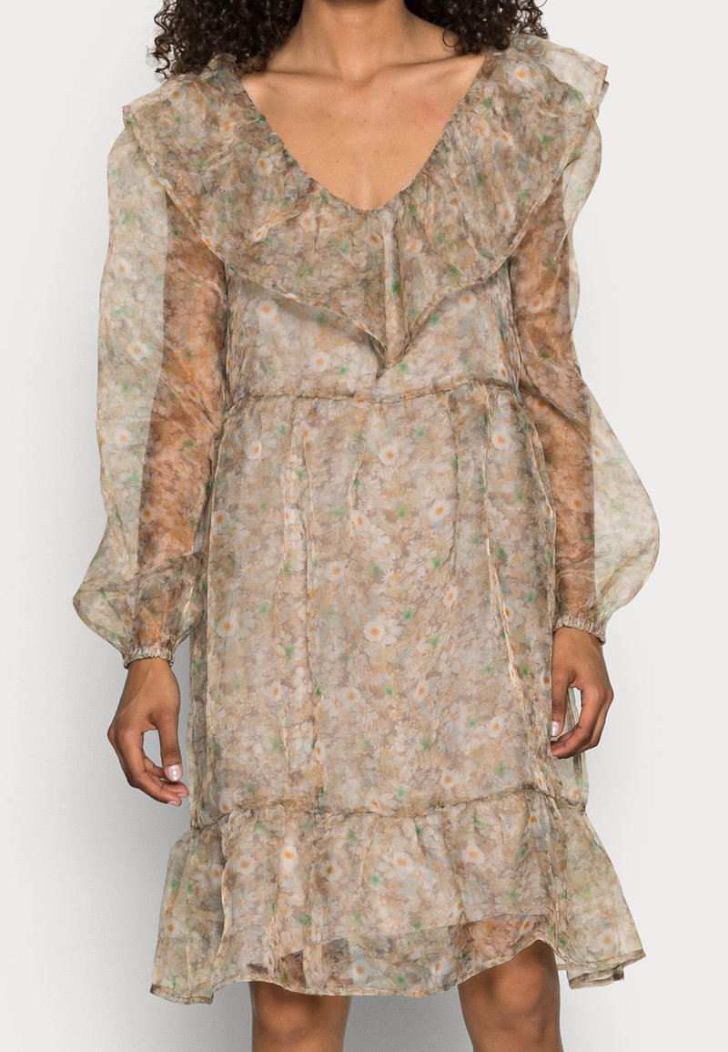 Robe fleurie en dentelle avec un col froncé, des manches longues et une jupe froncée. Elle présente un tissu beige clair orné de petites fleurs blanches et orange.