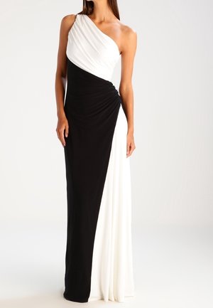 Vrouw draagt een zwart-witte een-schouder avondjurk tot op de grond met geplooide details bij de taille.
