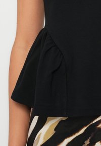 Black peplum top featuring gathered detailing at the waist, made from soft fabric, paired with a patterned skirt displaying earthy tones.