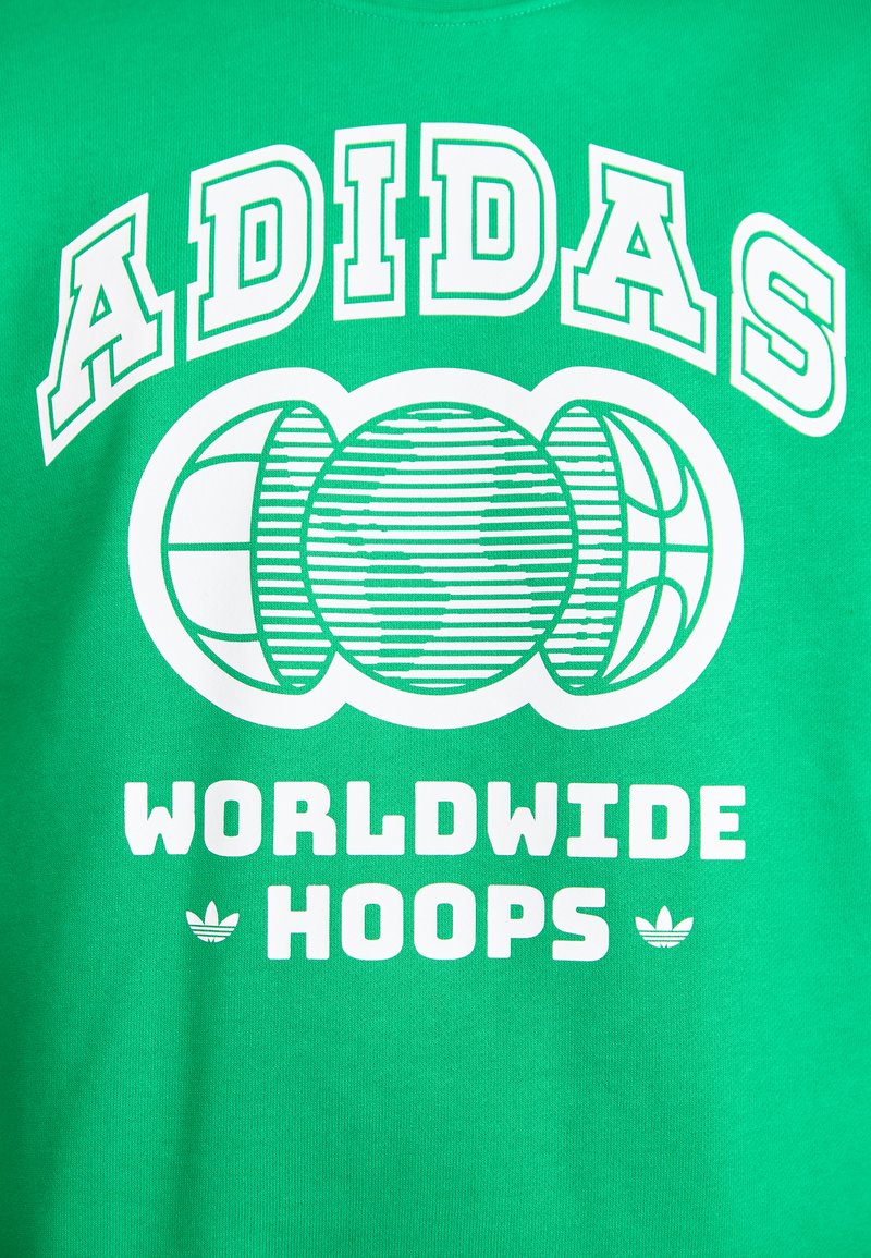 Groene katoenen t-shirt met witte tekst "ADIDAS WORLDWIDE HOOPS" en drie gestileerde basketbalgraphics. Ribbeltextuur op de stof.