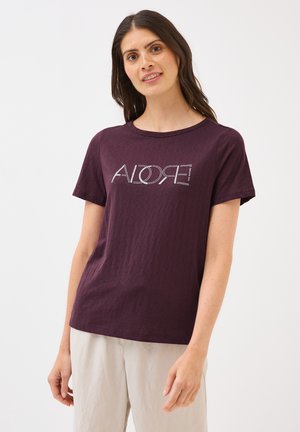 T-shirt à manches courtes bordeaux avec une finition texturée et 'ADORE' en impression argentée. Conception col rond et coupe décontractée. Porté avec un pantalon clair.