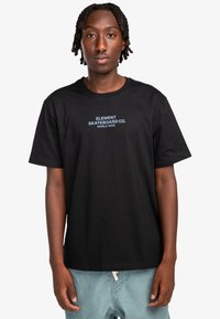 Black cotton t-shirt featuring "ELEMENT SKATEBOARD CO." in blue text on the front. Simple design with short sleeves and a crew neck.