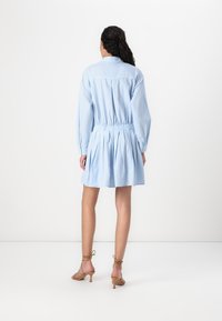 Vestido listrado azul claro com um corte descontraído, cintura franzida e mangas balão. Acabado com colarinho e comprimento até a metade da coxa.