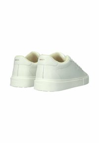 Witte lage sneakers met crèmekleurige voering, minimale stiksels en "BLCKSTN"-logo op de hielflappen.