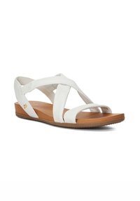 White leather sandals with cross-strap design, tan rubber sole, and gold accent. Flat heel and open-toe style.