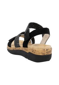Sandales noires avec des lanières tressées et une fermeture à crochets et velcro, semelle en liège et semelle noire texturée. Présente un talon épais pour plus de soutien.