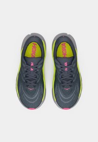 Grijze en neongele sportschoenen met een gestructureerde bovenkant, ronde neus, roze accenten en standaard veters. Platte zool met een lichte hak.
