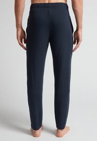 Navyblauwe, elastische broeken gemaakt van een gladde, lichte stof, met zijzakken en een taps toelopend ontwerp.