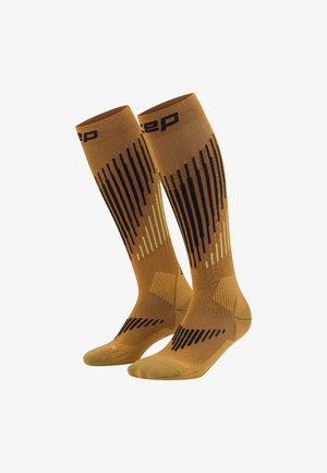 Kompressionssocken in goldbraun mit gestreiften Mustern in Schwarz und hellem Beige. Glatte Textur, knielange Ausführung, verstärkte Zehen und Fersen.