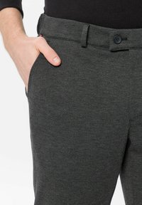 Anthrazitfarbene Hose aus einem weichen, strukturierten Stoff mit Knopfverschluss, Seitentasche und elastischem Bund.