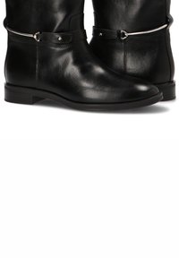 Botines de cuero negro con un acabado liso, que cuentan con una correa de acento plateada y una puntera redondeada sobre un tacón bajo y robusto.