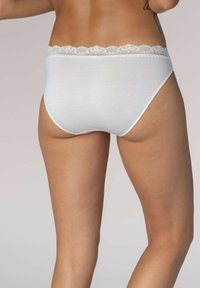 Slip in cotone bianco con ampia fascia in pizzo, caratterizzati da una superficie liscia e un design a piena copertura. La vista dal retro mette in evidenza la forma aderente.