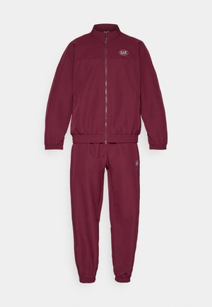 Bordo treniruotė su užtrauktuku ir elastingomis kelnėmis. Striukė turi aukštą apykaklę ir logotipo detalę ant krūtinės.