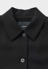 Zwarte jas met kraag van gladde stof, voorzien van een enkele knoopsluiting en een binnenin genaaide label.