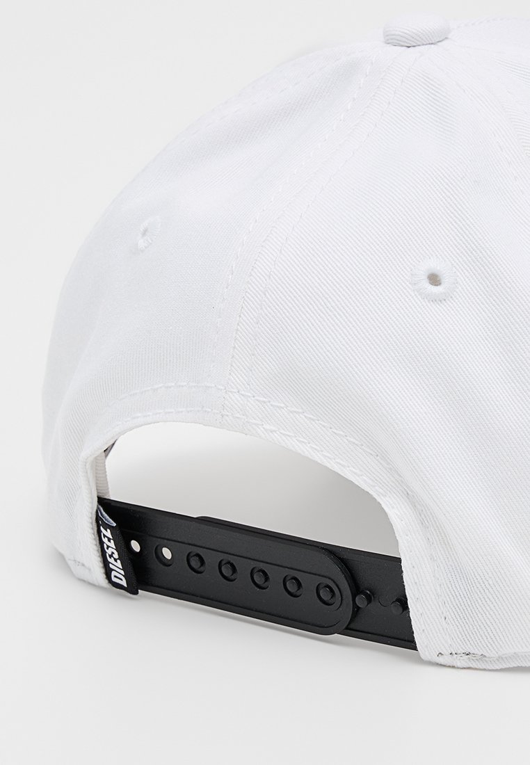 Weißes Stoffcap mit einem schwarzen verstellbaren Riemen hinten, der mehrere Löcher und ein Markenschild aufweist. Texturierte Oberfläche des Materials.