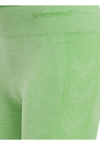 Collant verde chiaro con vita a costine, caratterizzati da un motivo geometrico e una consistenza liscia. Il logo "hummel" è visibile sulla vita.