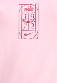 Roosa puuvillane T-särk, millel on punane graafiline disain, kus on kirjas "Nike", "1972" ja logo ristkülikukujulises raamistikus ning laurelid.
