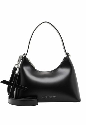 Sac à main noir brillant avec une poignée supérieure courbée, un grand pendentif en forme de croix et un petit texte argenté près du bas indiquant SURI FREY x ALEXANDER.