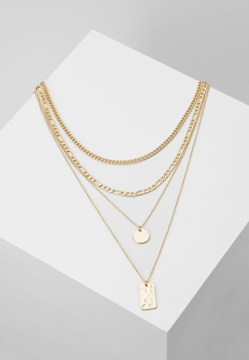 Collares de oro laminado que presentan varios estilos de cadena: una cadena de eslabones gruesos, una cadena fina con un colgante circular y un charm rectangular texturizado.